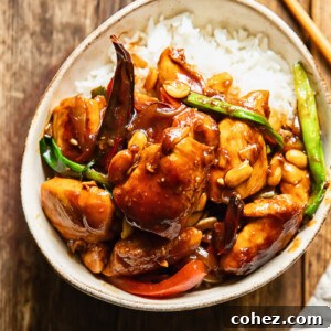 Top down shot of szechuan chicken with green onions and peppers on a bed of rice in a small bowl