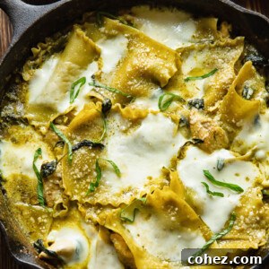 Top down shot of white chicken skillet lasagna in a pan topped with melted cheese and fresh basil