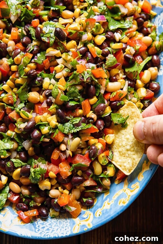 Close up shot of someone scooping up cowboy caviar salad with a corn tortilla chip