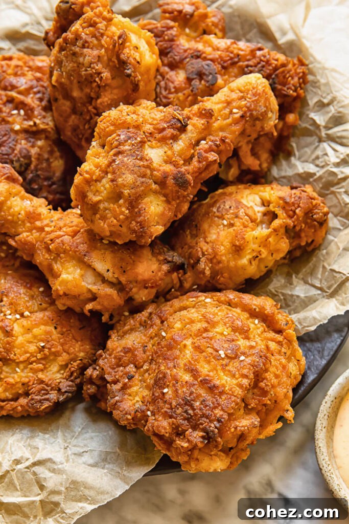 Close up shot of buttermilk fried chicken drumsticks with crispy skin piled on a plate