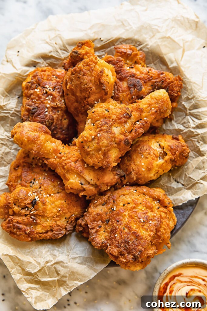 Top down shot of buttermilk fried chicken stacked on a plate next to chilli mayo