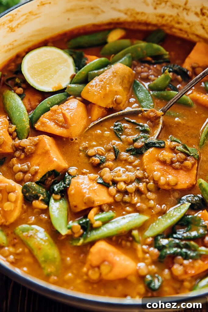Sweet potato and lentil curry in a pan with serving spoon