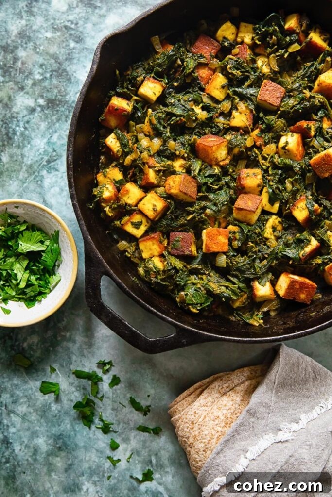Close-up shot of creamy Saag Paneer in a cast iron pan, showing paneer cubes and vibrant spinach.
