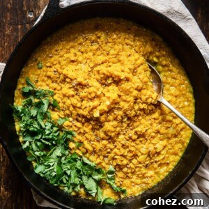 Top down of a pan of red lentil dahl on a wooden surface with parsley on top