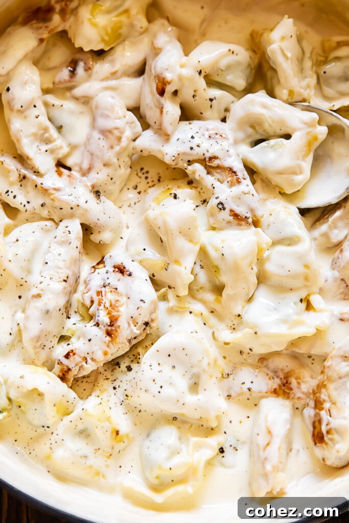 Close up shot of creamy chicken tortellini Alfredo topped with ground black pepper