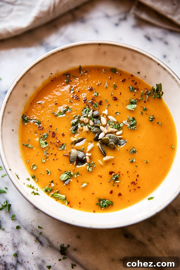 Zingy Sweet Potato Carrot Soup 2 A beautifully presented bowl of Sweet Potato and Carrot Soup, garnished with a sprinkle of mixed seeds and fresh green herbs, inviting a first taste.