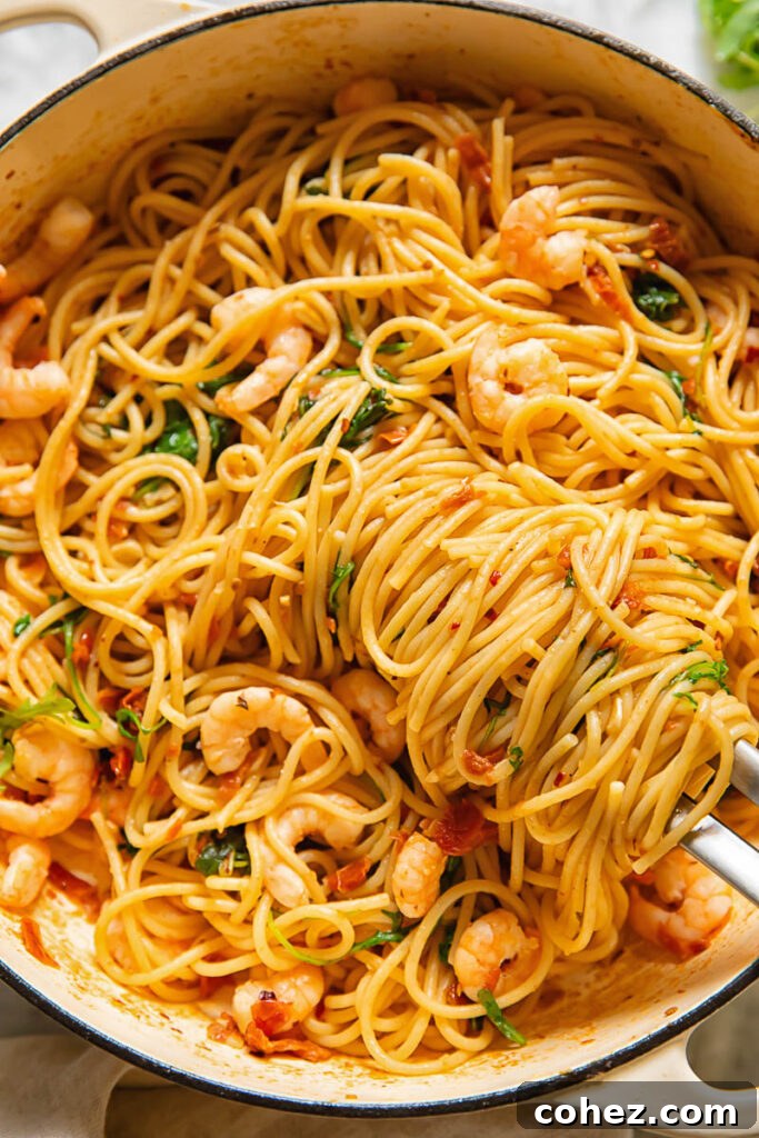 Top down shot of sun dried tomato pasta in a pan with shrimp, chilli and arugula