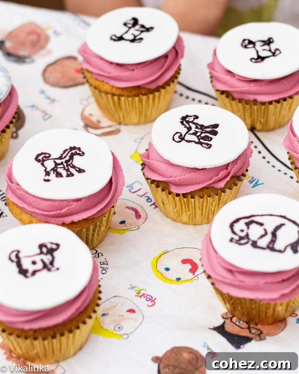 Max's Wild Rumpus Bites 2 Top down view of pink iced cupcakes with adorable animal designs stamped on fondant medallions