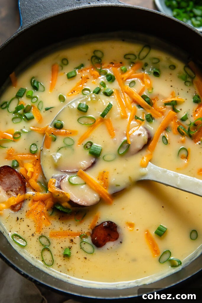 Top down shot of kielbasa soup in smooth potato blended broth being scooped out of a large pot