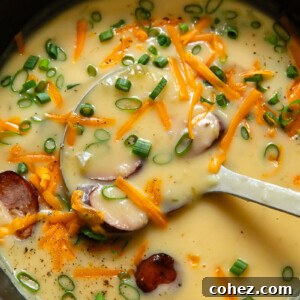 Top down shot of kielbasa soup in smooth potato blended broth being scooped out of a large pot