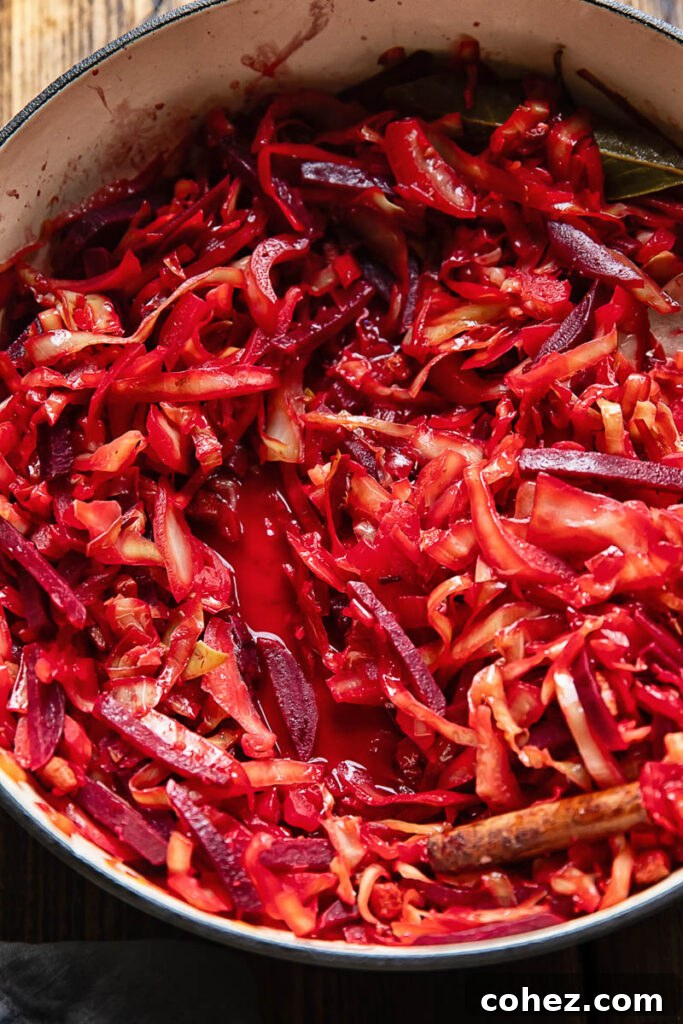 Close up shot of braised beets and cabbage in a pan topped with bay leaves and cinnamon