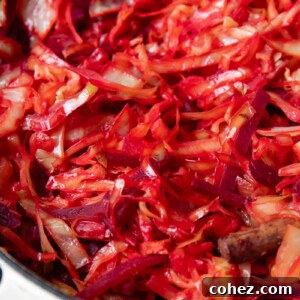 Close up shot of braised cabbage and beets in a large pot with bacon bits