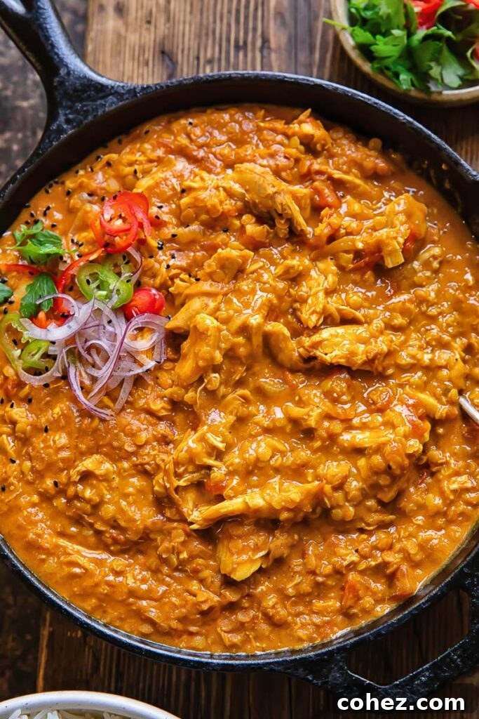 Close up shot of leftover turkey curry in a pan topped with freshly sliced onion and coriander