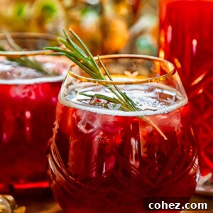 Side shot of pomegranate christmas punch in a glass with rosemary garnish