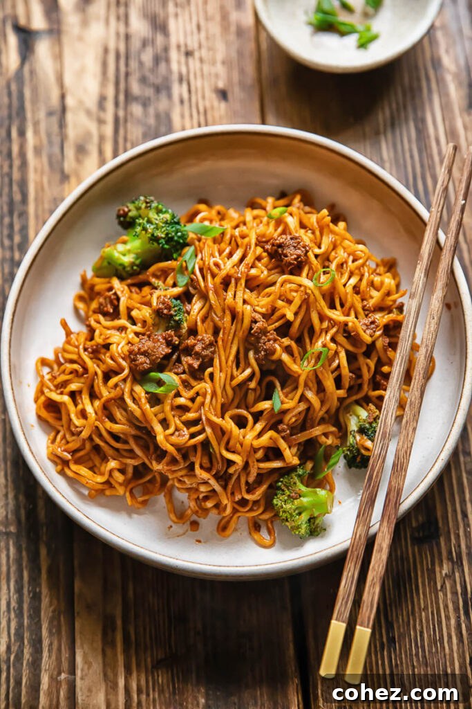 Top down shot of gochujang noodles with beef in a bowl with chopsticks