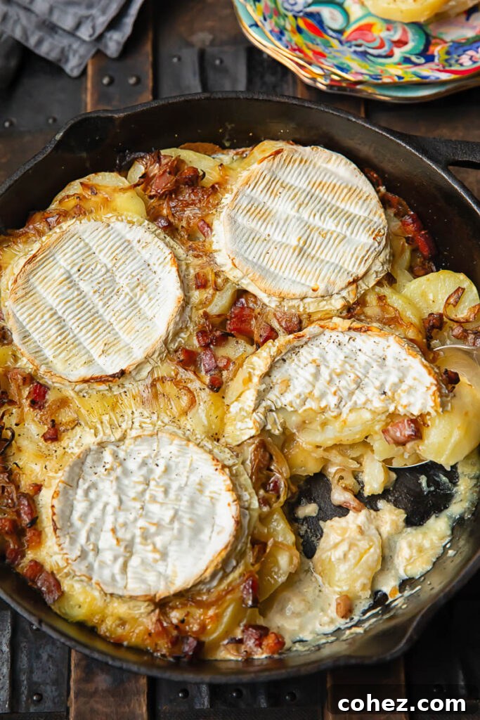 Top down shot of potato slices cooked in a pan with melted Camembert and bacon