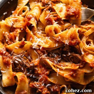 Close up shot of short rib ragu on a plate topped with grated Parmesan