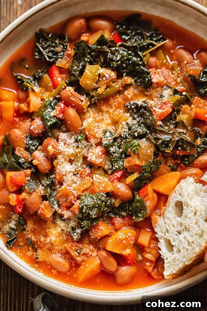 Close up shot of a slice of bread being dipped into a bowl of chorizo bean soup