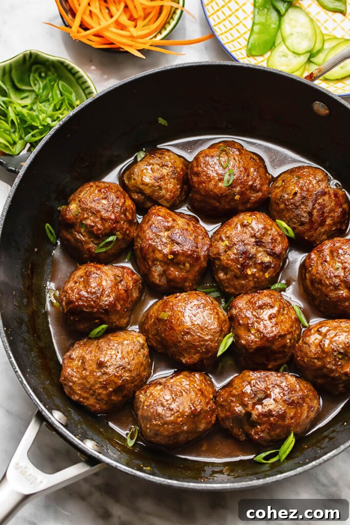 Sticky Sweet Teriyaki Meatballs 3 Top down shot of teriyaki meatballs in a wide pan topped with spring onions