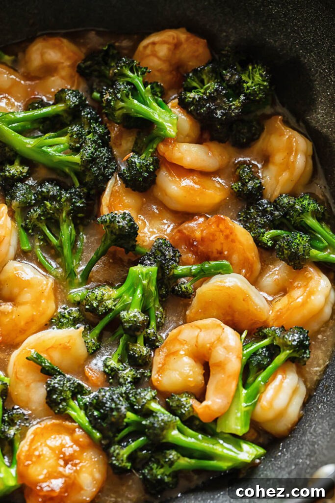 Close up shot of shrimp and broccoli stir fry in a pan, with the sauce bubbling around the ingredients.