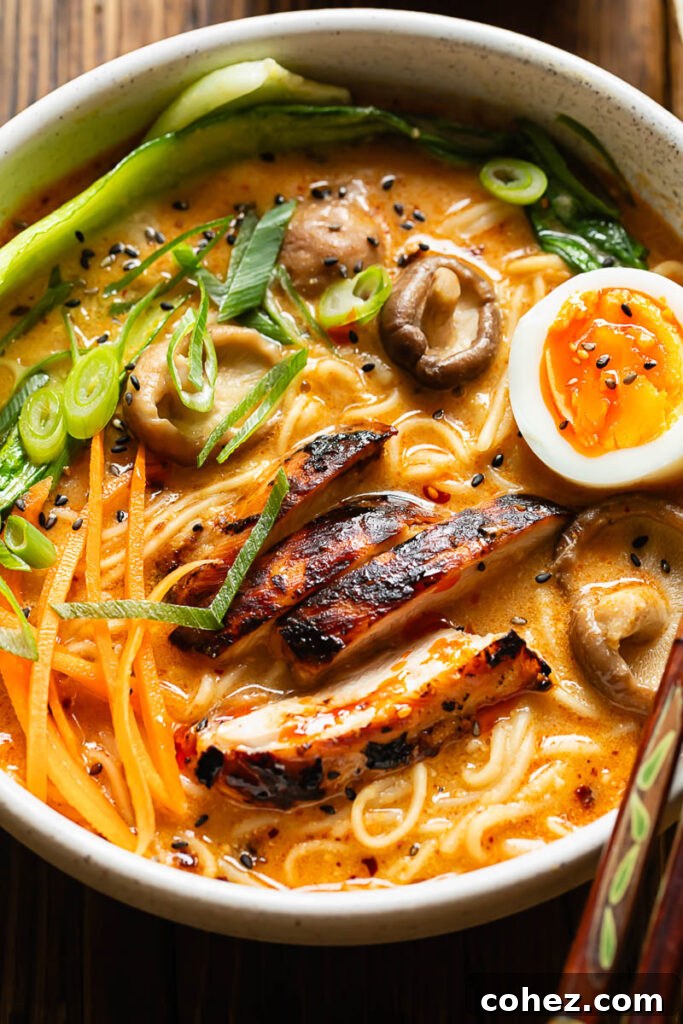 Close up shot of chicken ramen with carrots, mushrooms and a boiled egg, showing the vibrant colours and textures.