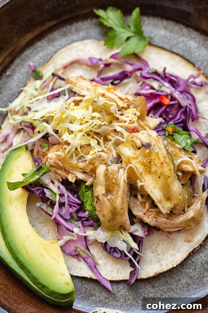 Top down shot of a taco on a plate with salsa verde chicken and fresh veg
