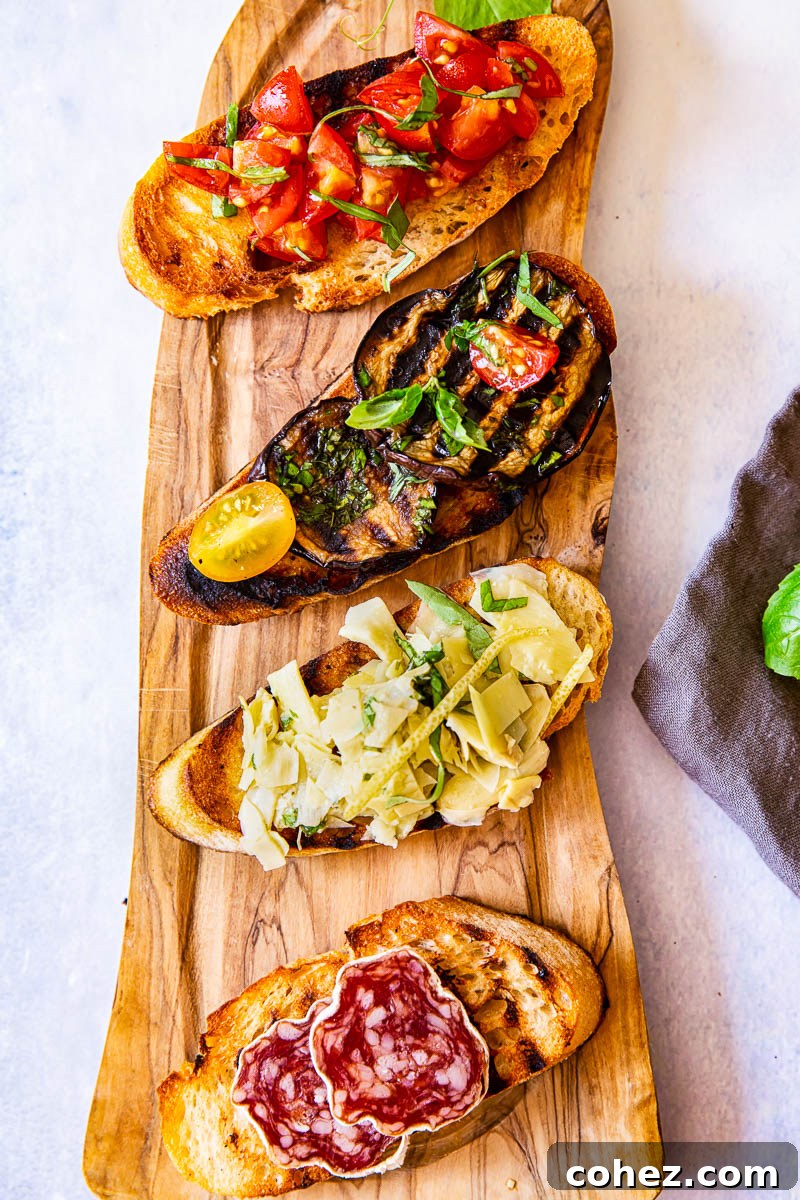 Four bruschetta slices with various toppings on a rustic wooden board.