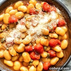 Top down shot of butter beans with cherry tomato sauce in a pan