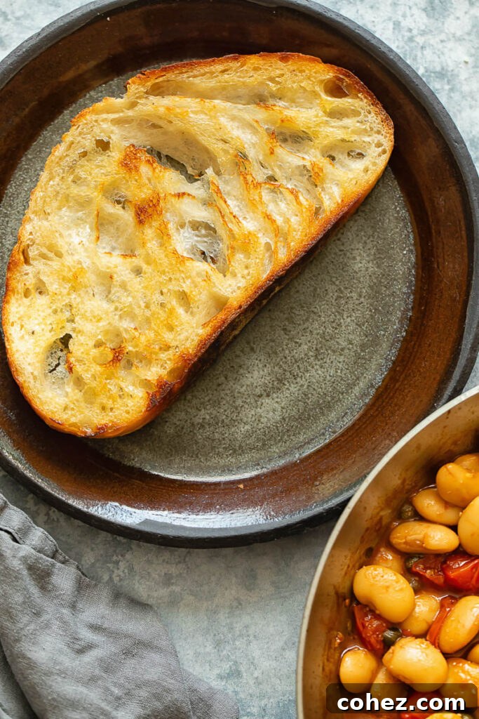 Shot of a slice of toast next to a plate of posh beans