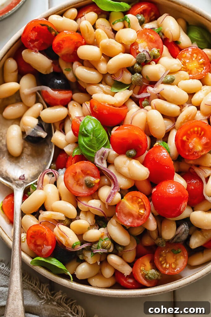 Vibrant White Bean Puttanesca 3 Close up shot of white bean salad with a serving spoon