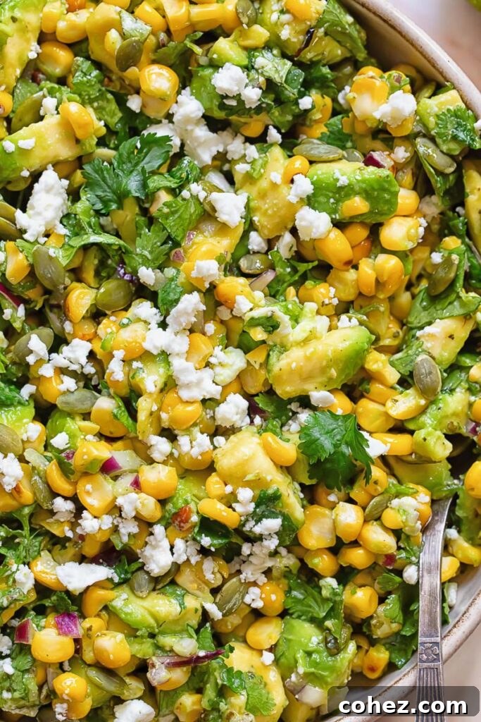 Close up of avocado corn salad topped with white cheese and cilantro
