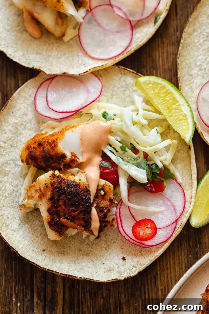 Cajun Fish Tacos 2 Top-down view of several blackened fish tacos with various fresh toppings and lime wedges