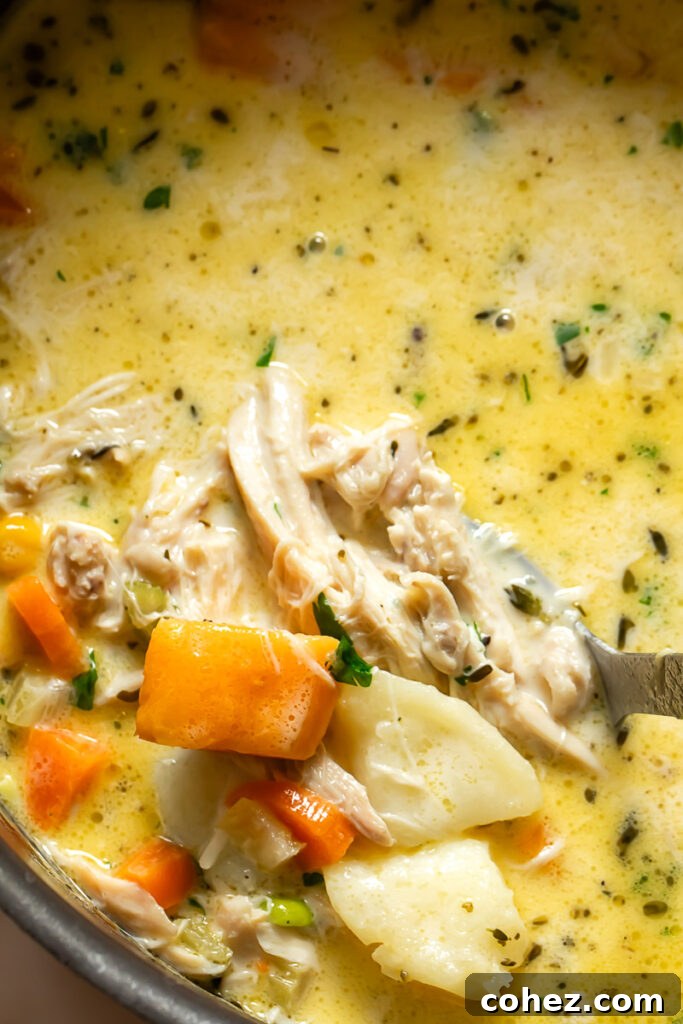 Close up shot of creamy turkey chowder with carrots and potatoes in a large pot, steaming gently.