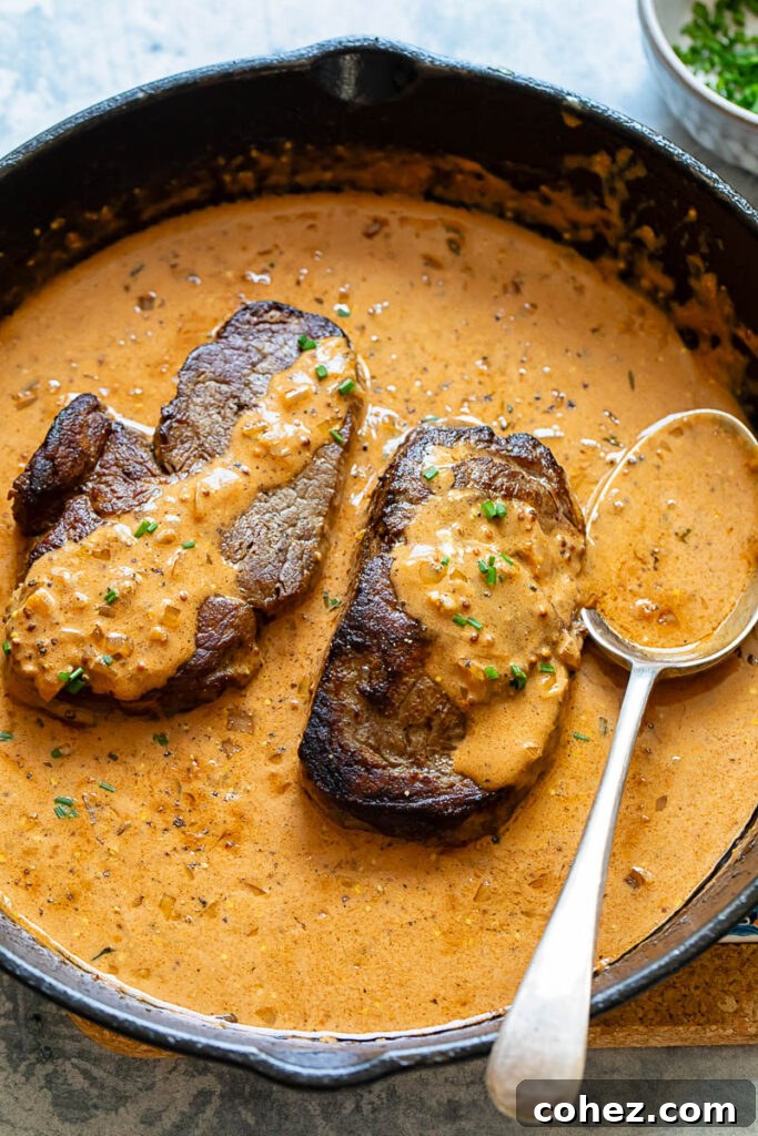 Close-up of two seared fillet steaks in a cast iron pan, ready for the Diane sauce to be built around them.