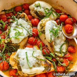 Chicken Caprese in a pan with cherry tomatoes, basil, and melted mozzarella