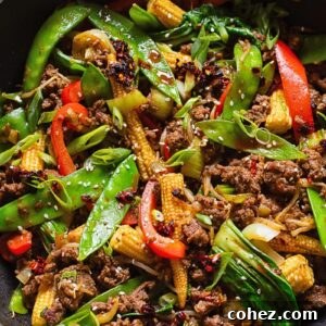 Top-down shot of ground beef stir fry brimming with colorful vegetables in a large pan