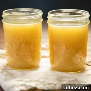 Two clear glass jars filled with golden, homemade turkey stock, ready for use in various culinary applications.