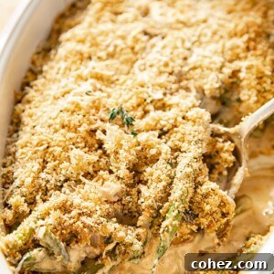 A bubbling fresh green bean casserole covered with a golden Parmesan breadcrumb topping, in a white baking dish.