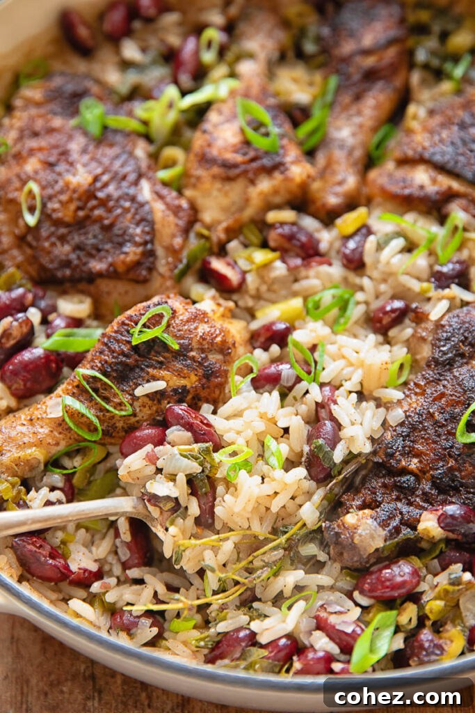 A close-up view of the perfectly cooked one-pot Jamaican Jerk Chicken with Rice and Peas, highlighting the tender chicken and moist, flavorful rice