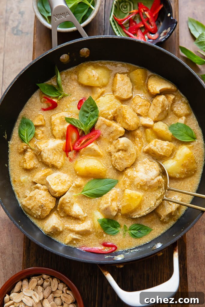 Close up of yellow chicken curry with potatoes and chilli in a pot
