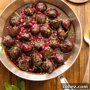 Delectable meatballs generously coated in a shimmering sweet and sour pomegranate sauce, served on a rustic wooden table.