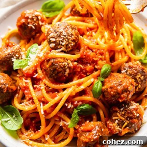 Bucatini pasta generously coated in a rich Amatriciana sauce with tender meatballs, beautifully garnished with fresh basil leaves.
