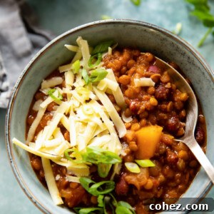Bowl of vegetarian chili with grated cheese and a spoon, highlighting its wholesome ingredients.