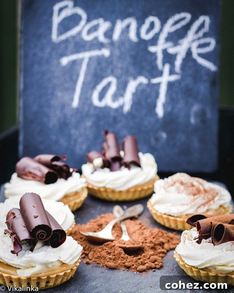 Side shot of banoffee tarts with chocolate powder in the middle on a blue surface, showcasing perfect layers.