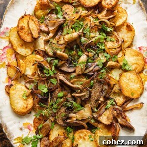 Top-down view of deliciously oven-fried potatoes with mushrooms and onions, garnished with fresh herbs.