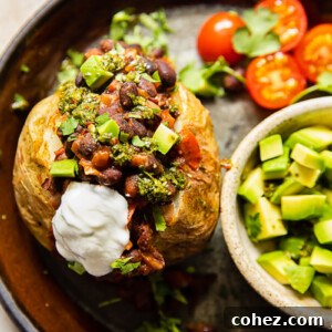 A perfectly baked jacket potato generously topped with spicy baked beans and vibrant chimichurri sauce.
