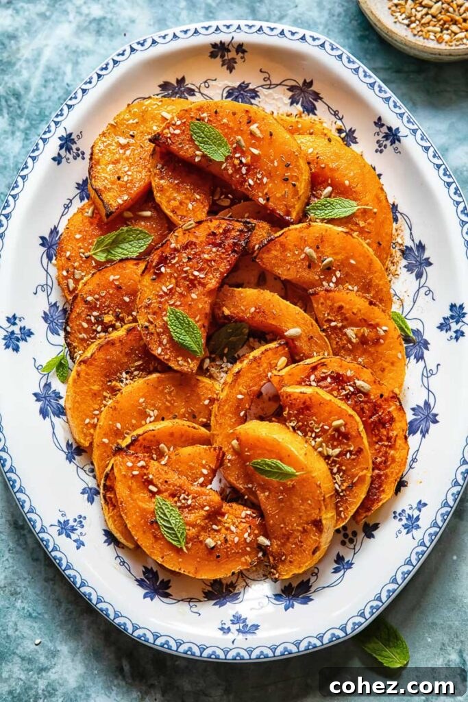 roasted butternut squash slices on a plate with basil garnish