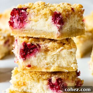 Three almond raspberry cheesecake bars stacked on top of each other, showcasing their creamy filling and crumbly topping.