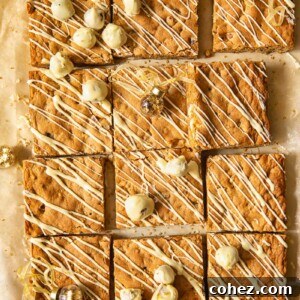 Top-down view of square-cut brown butter hazelnut blondies, showing the hazelnuts and white chocolate drizzle.