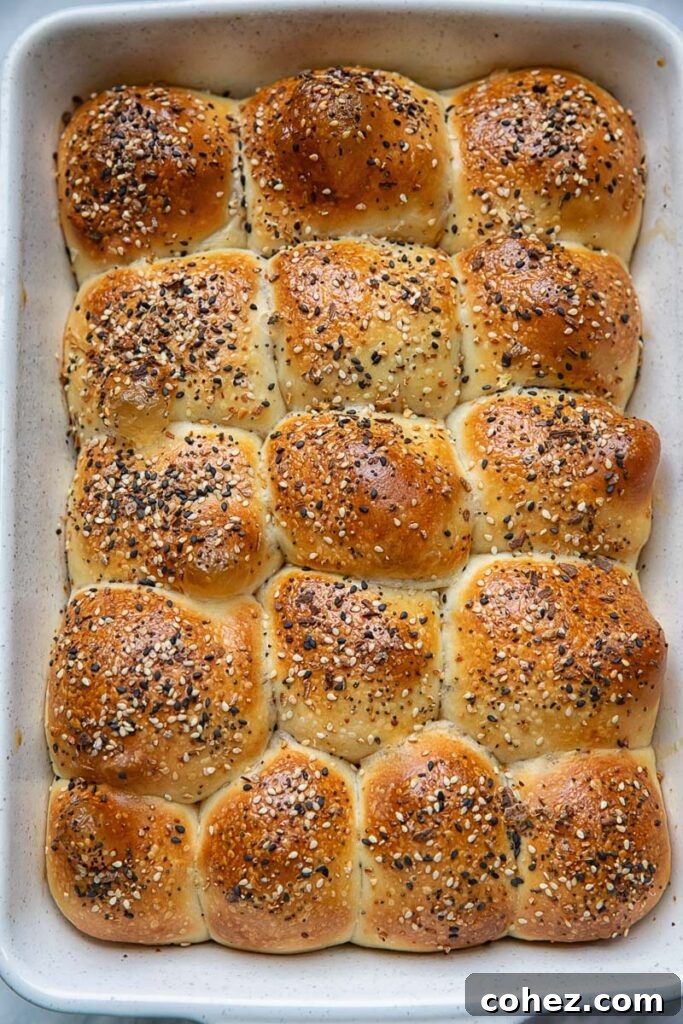 Wake Up To Everything Bagel Dinner Rolls 2 Top-down view of freshly baked, golden brown Overnight Dinner Rolls in a white baking dish, generously sprinkled with Everything Bagel seasoning.